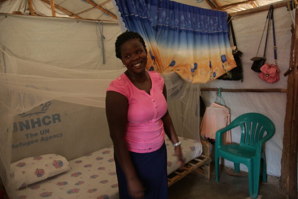 Woman who is healthcare worker stands in tent living quarters at Palorinya refugee Camp
