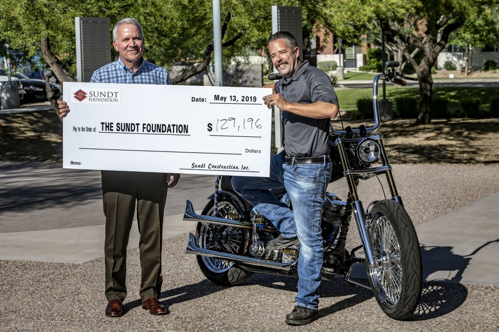 Sundt CEO Mike Hoover and Danny Gumm hold the final check addressed to the Sundt Foundation.