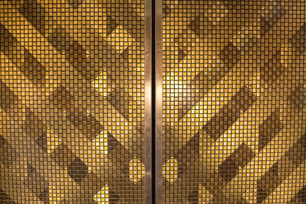 Las puertas de ascensor originales del edificio Blue Flame son únicas y tienen un patrón geométrico dorado único.