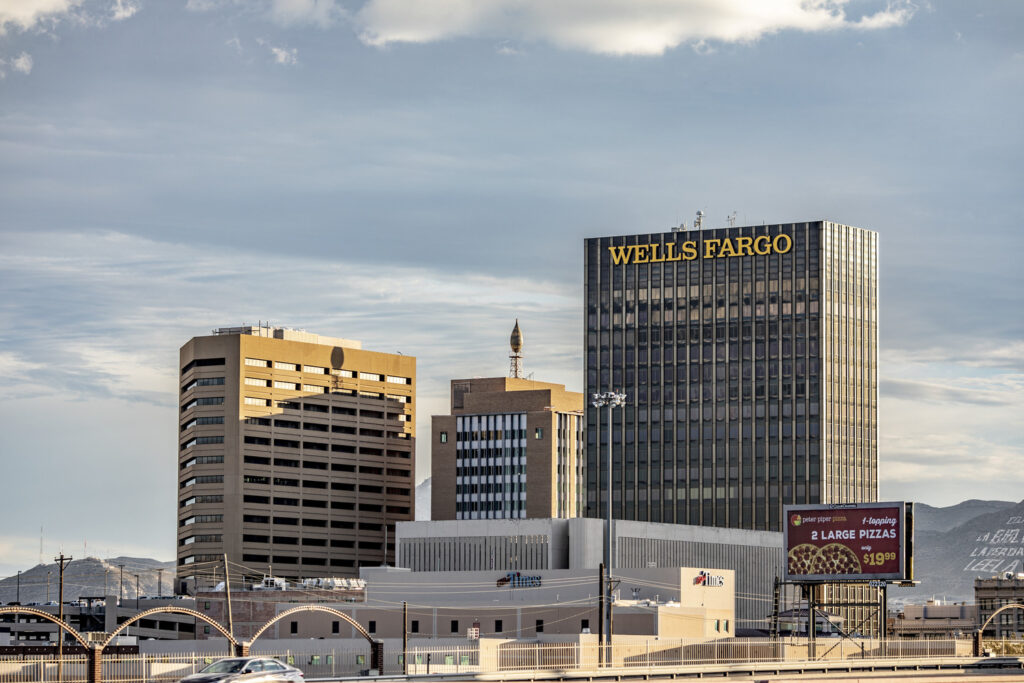 edificio de llama azul en medio del horizonte de El Paso con otros rascacielos, incluido el edificio Wells Fargo a última hora de la tarde