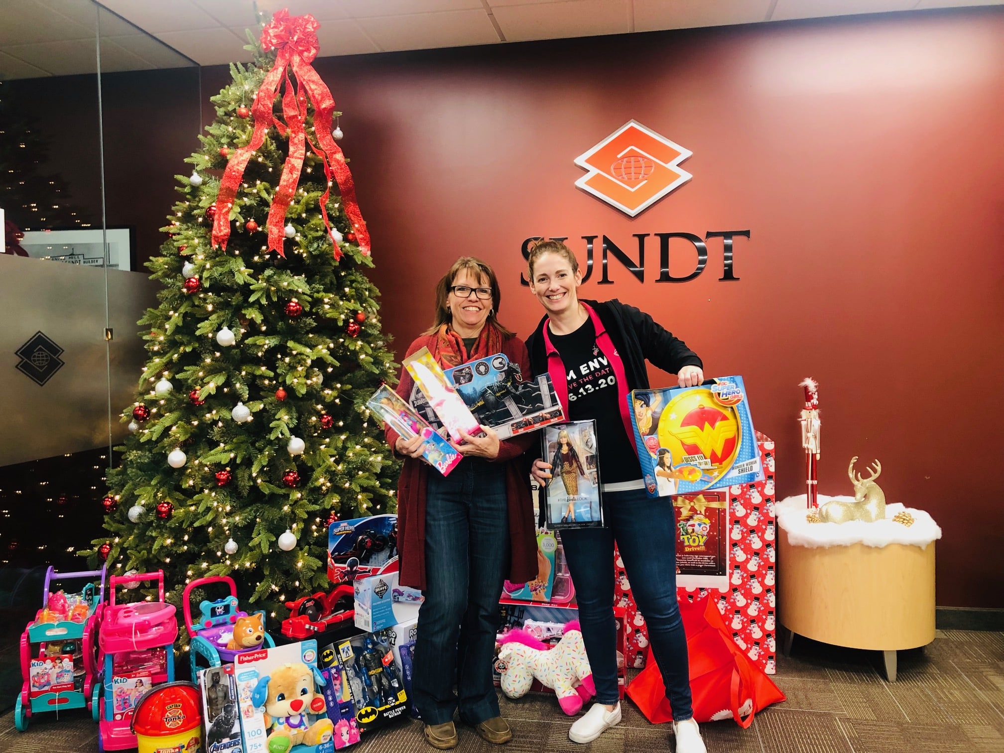 two people standing in front of a christmas tree with toys