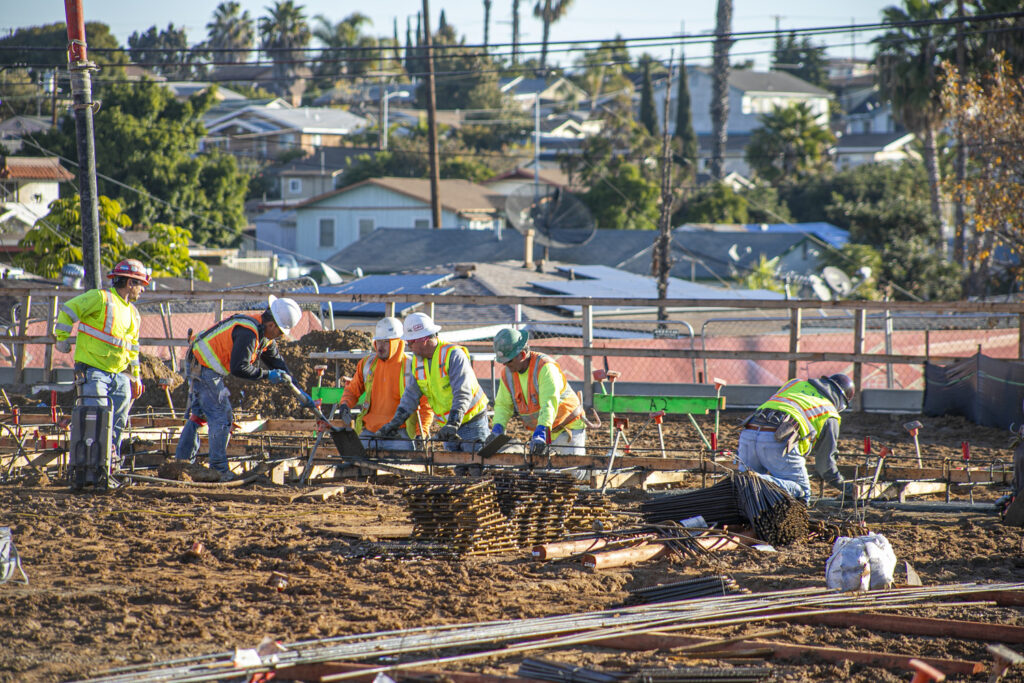 a crew pours concrete foundations for four new school buildings