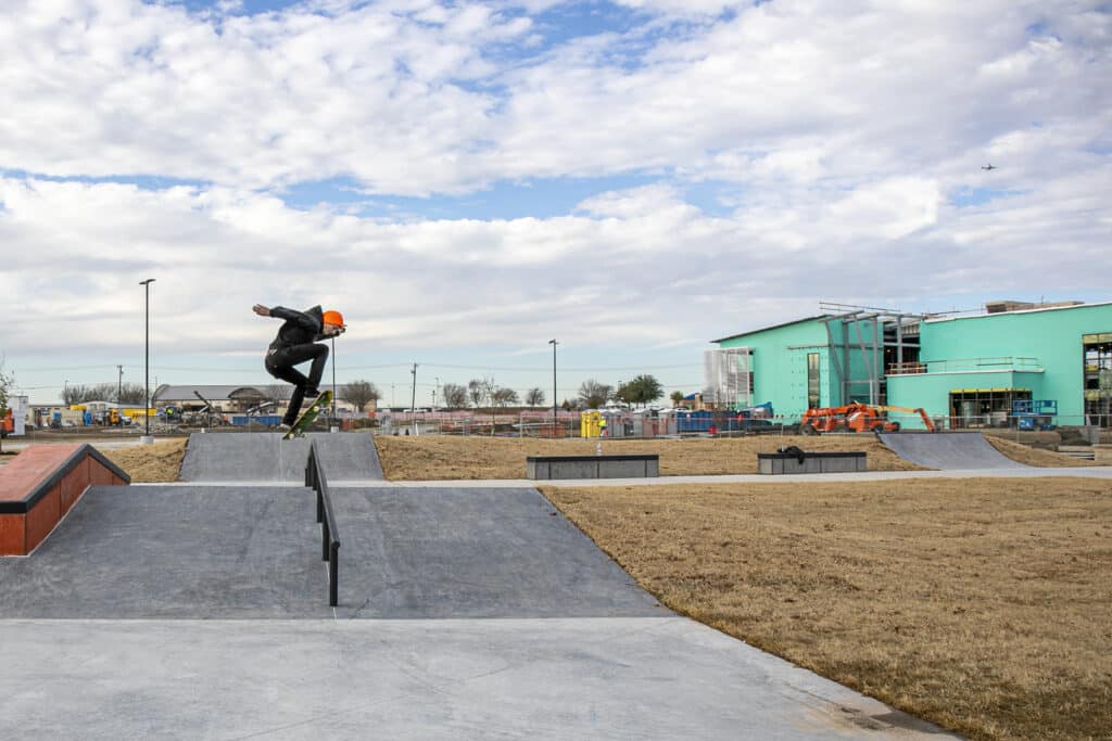 skateboarder at arlington Texas Beacon Rec center skatepark, pictured here mid-air setting up for a frontside boardslide