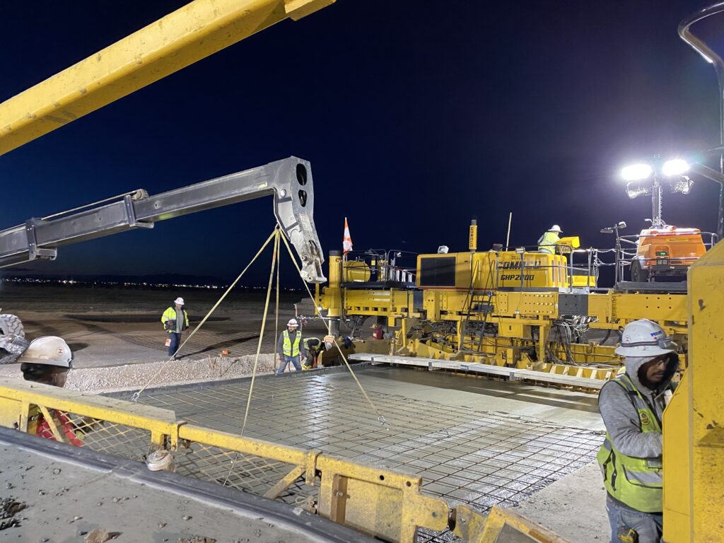 night shot of crews on two paving machines performing double strikeoff paving at biggs army airfield in El Paso Texas