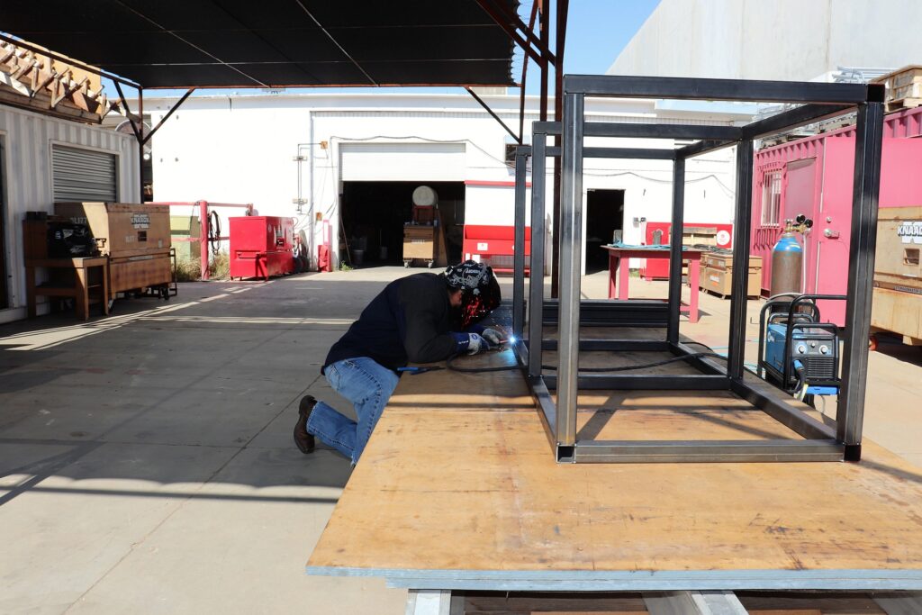 Craft Training Instructor Josue Ponce welds 2 inch square tube into a bed/desk combo