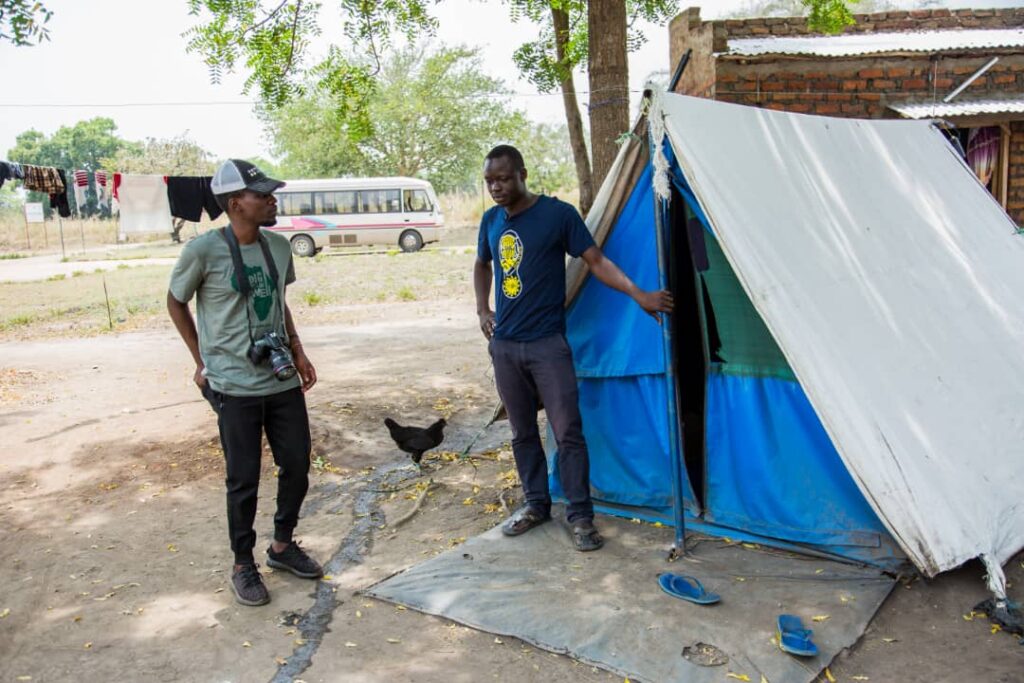 photographer talks with a healthcare worker next to the tent where he is living