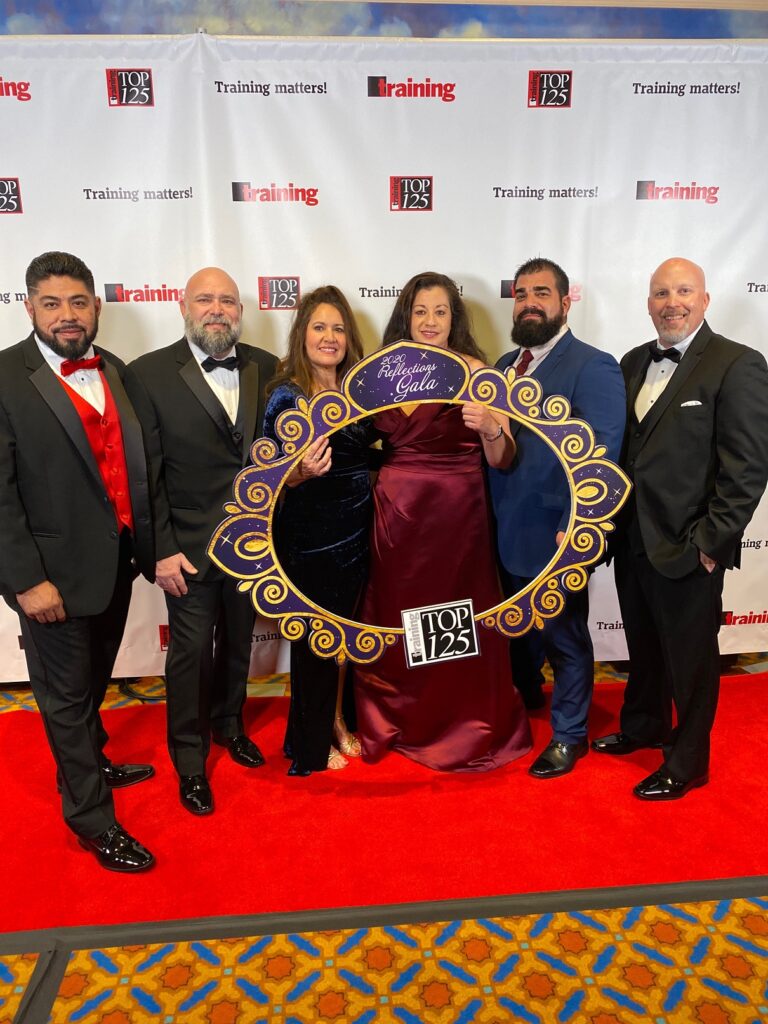 Sean and craft Instructor Josue Ponce stand with colleagues in Sundt's Admin Workforce Development Team at the Top 125 Awards