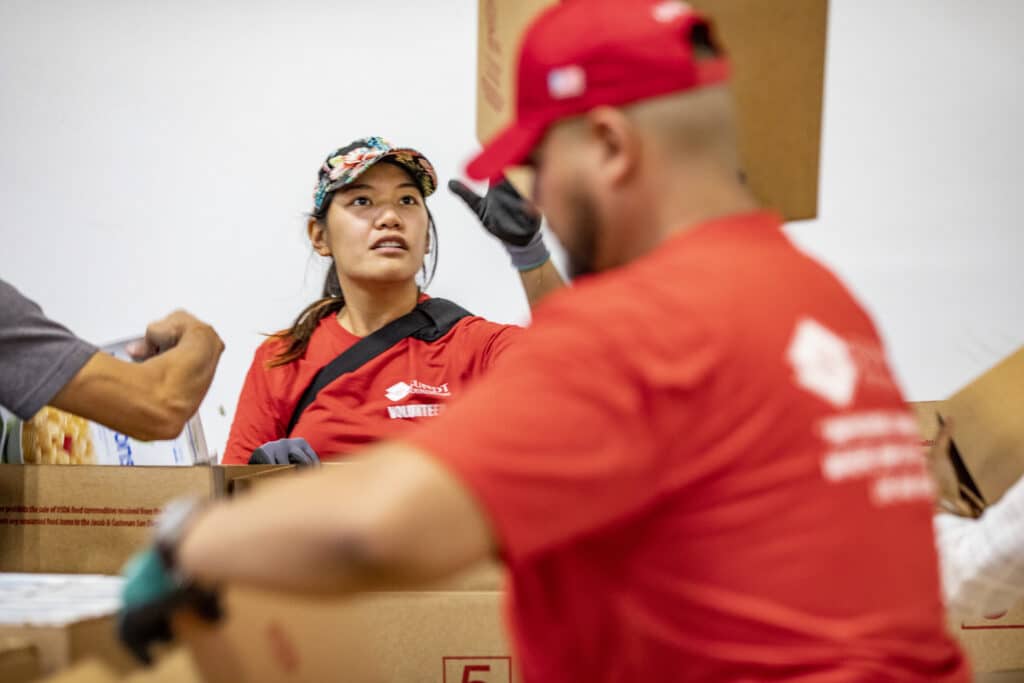 voluntario tira una caja vacía mientras empaca alimentos en la línea de montaje del banco de alimentos