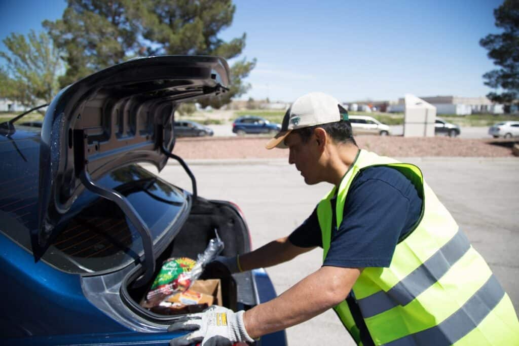 Un voluntario carga comida en la cajuela del automóvil de una familia en El Pasoans Fighting Hunger en El Paso, Texas