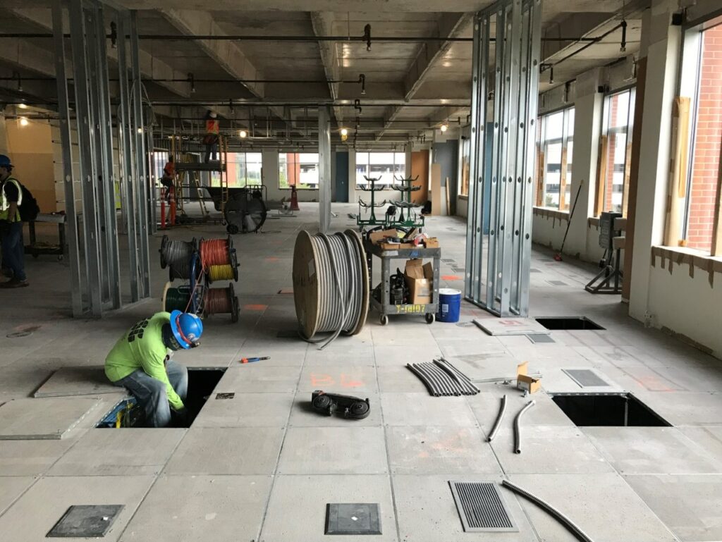 an electrician installs new cabling under the west fork tower office space's raised-access flooring