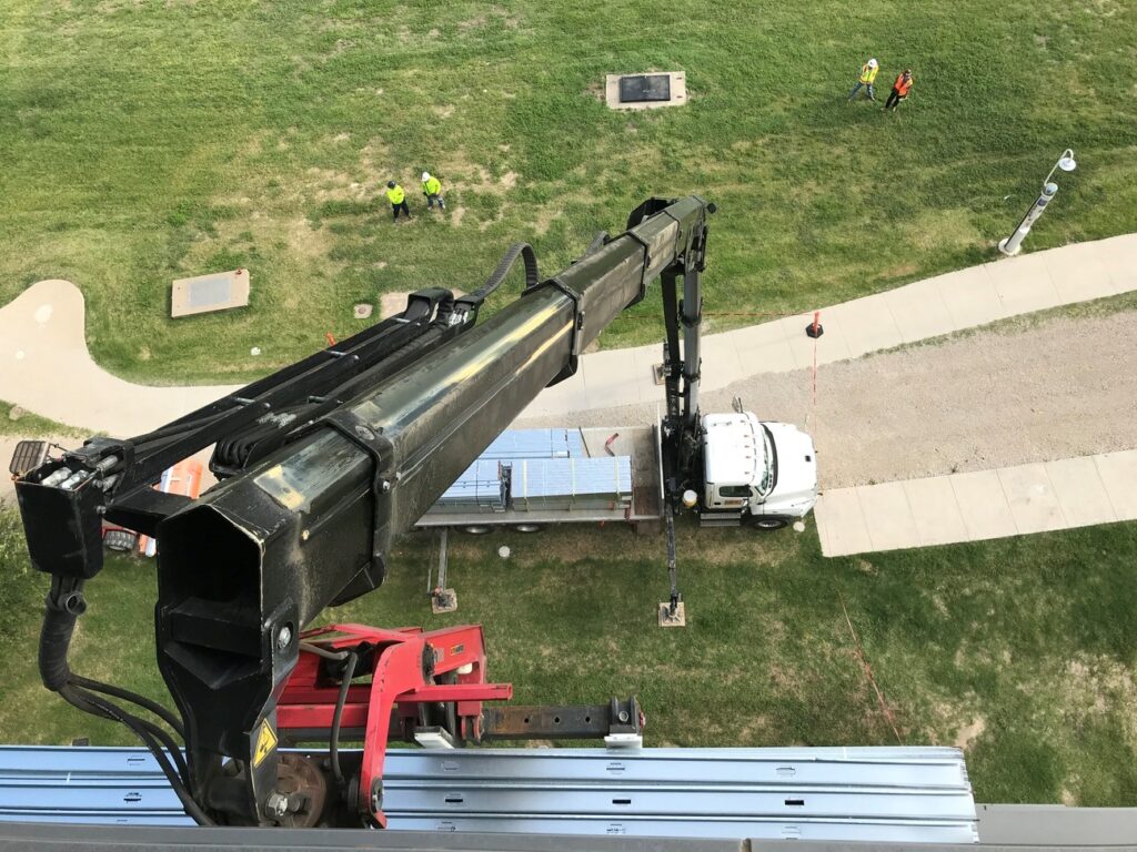 A boom truck operator lifts a pallet of metal studs up to framing crews on the fifth floor during renovation work at Tarrant County College's Trinity River Campus in downtown Fort Worth, Texas.