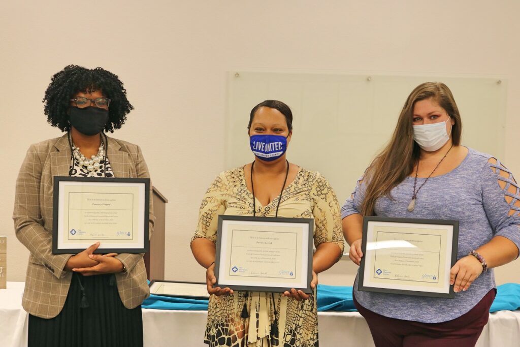 Three recent graduates of Grace Like Rain's financial literacy course proudly display their certificates of completion. 