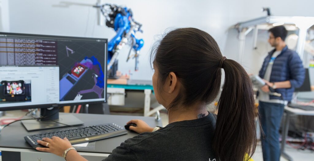 woman and man test robotic arm in laboratory facility