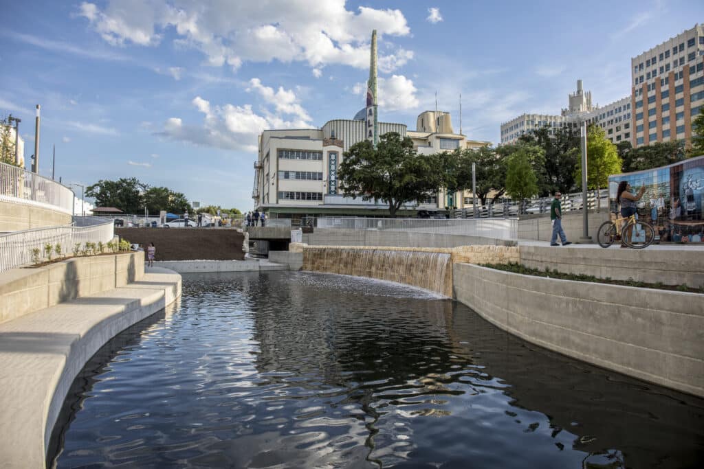 En el nuevo Parque Cultural San Pedro Creek, la gente ve un mural en honor al histórico Teatro Alameda de San Antonio junto a la vía fluvial de San Pedro Creek.