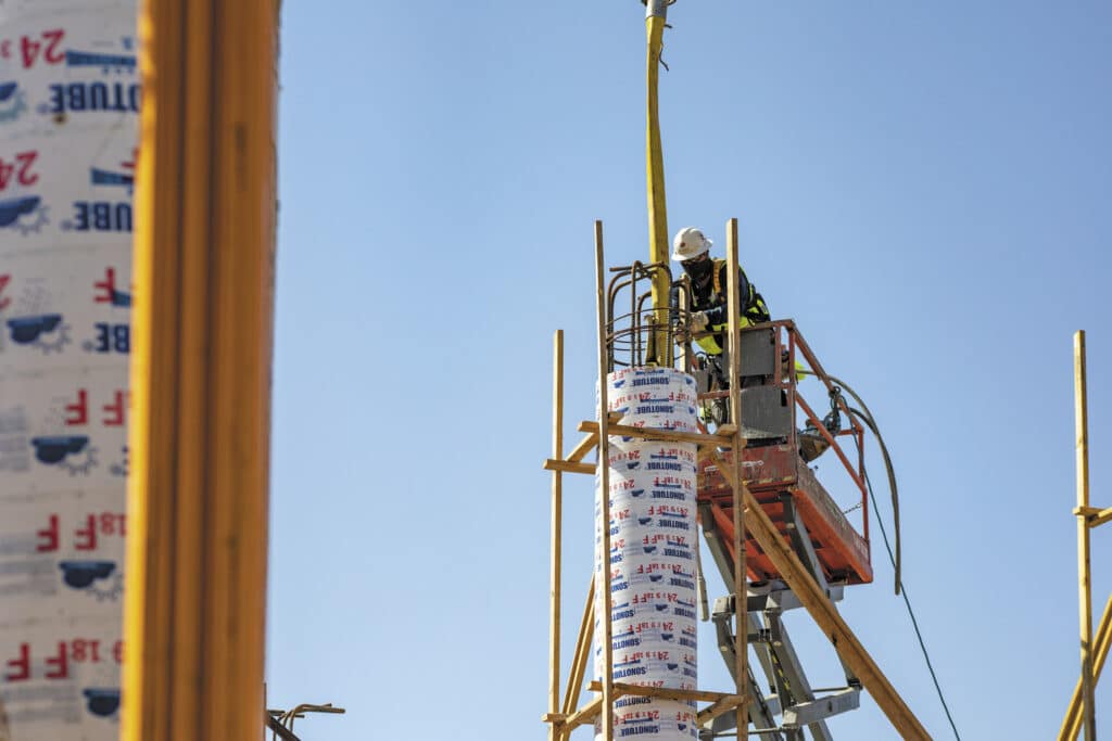 Se muestra a un trabajador de concreto colocando una columna en el tercer piso de Centennial Hall, donde ahora se encuentran los laboratorios de enfermería especializada y las áreas de colaboración.