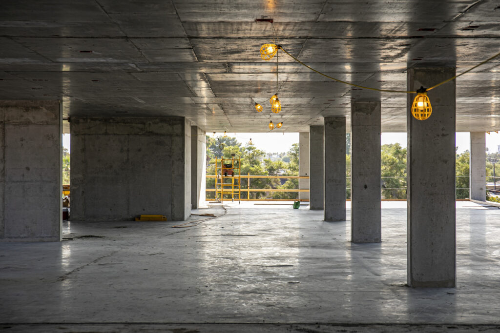 interior view showing polished concrete floor and exposed concrete ceiling inside on second floor of in-progress monastery apartment building
