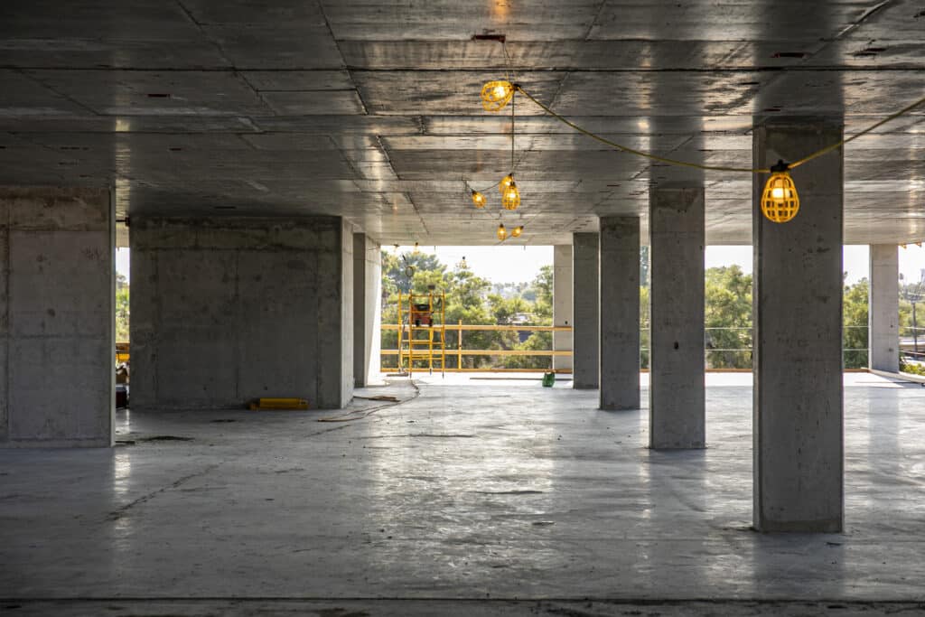 vista interior que muestra el piso de concreto pulido y el techo de concreto expuesto en el interior del segundo piso del edificio de apartamentos del monasterio en progreso