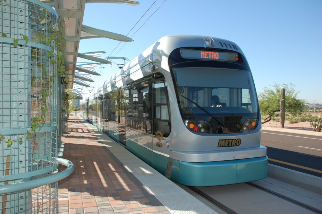 light rail train pulling up to platform at station in phoenix