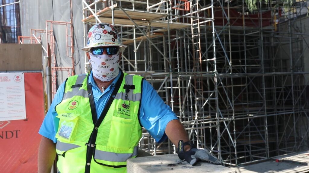 Mark Bakeman in PPE on bridge in downtown San Antonio outside of Canopy Hilton hotel
