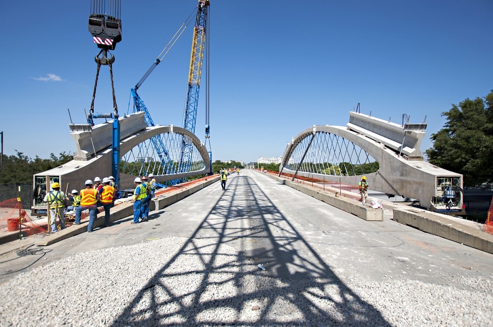 construction of Ft Worth 7th Street Bridge shows cranes setting precast concrete and steel arches