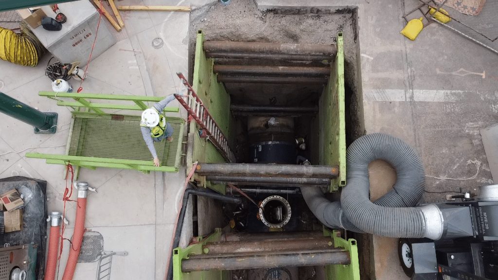 sundt employee-owner looks down at open trench where 66 inch water main is being installed