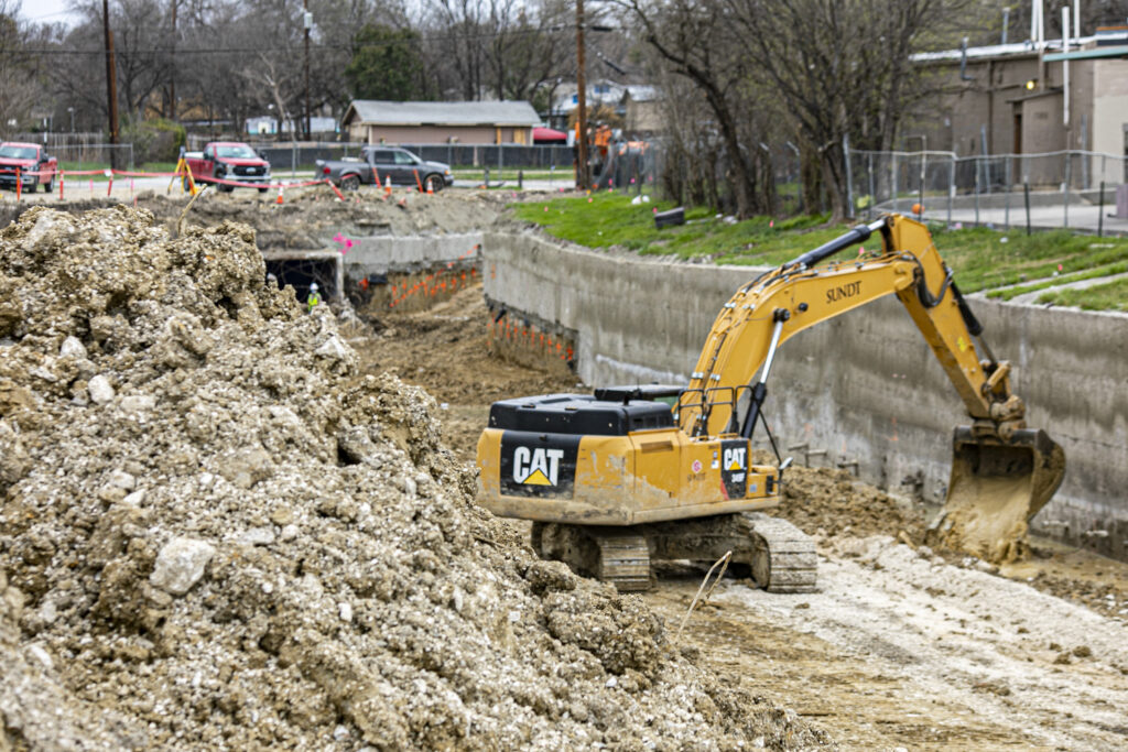Sundt CAT excavator digs out channel bottom at seeling channel in San Antonio