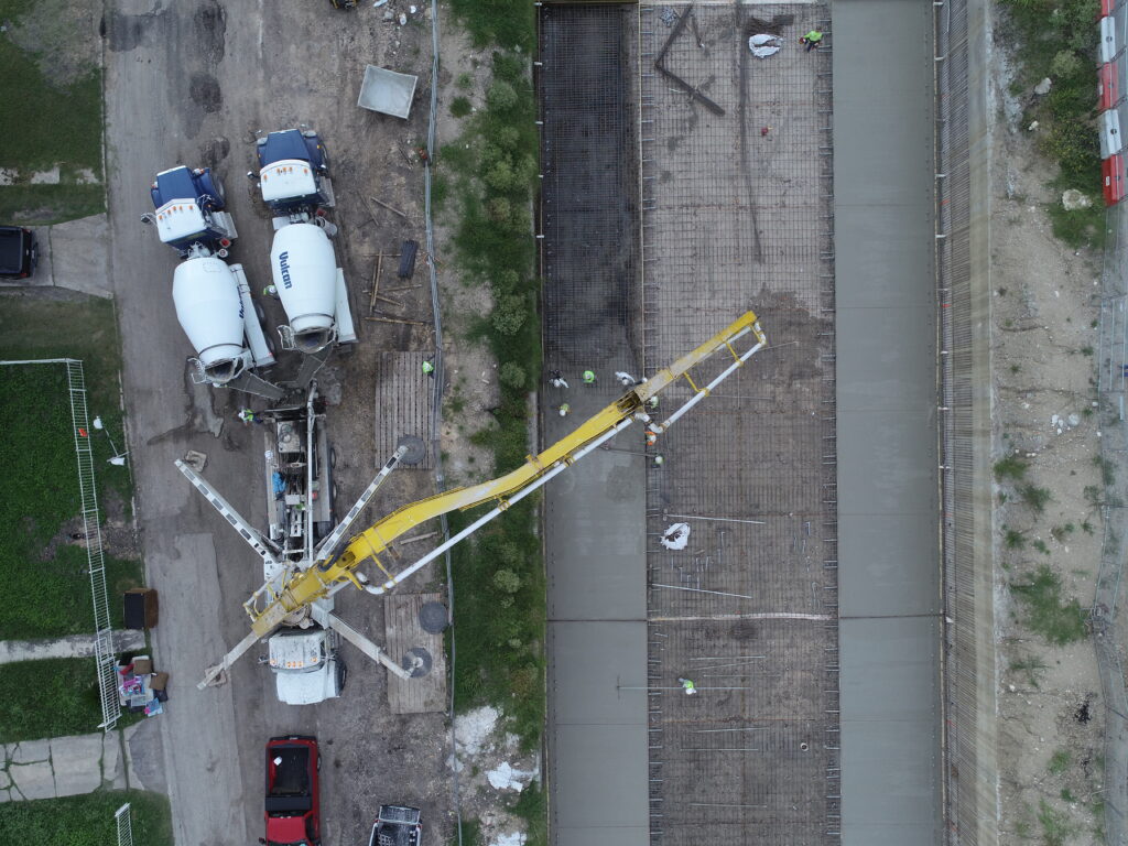 dos camiones mezcladores alimentan un camión bomba de hormigón para verter la losa del canal en Seeling Channel San Antonio