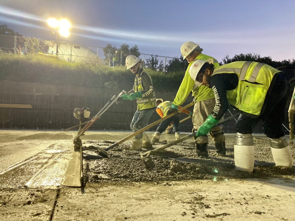 Los empleados-propietarios de Sundt trabajan juntos para terminar el concreto en la colocación final de la losa del canal.