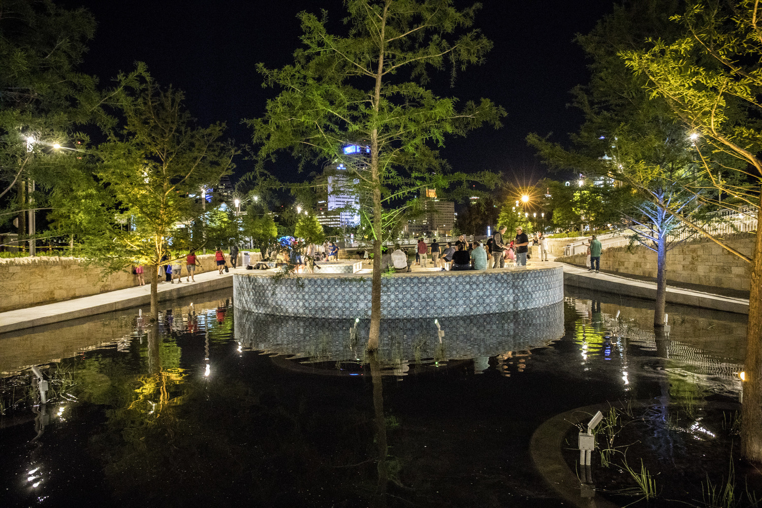 parque cultural san pedro creek con árbol y área de descanso llena de gente