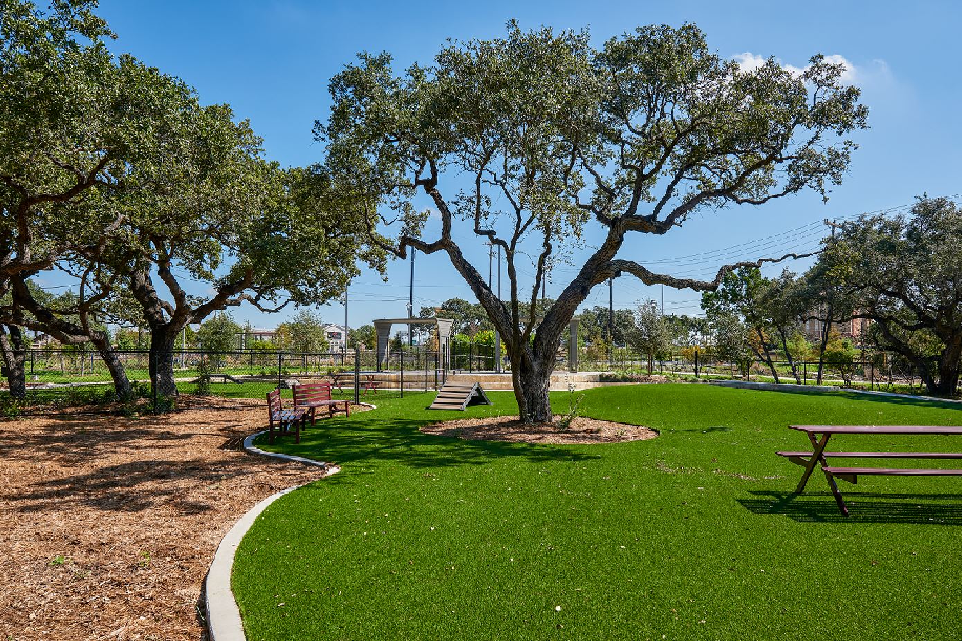 La Cantera Dog Park with grass, picnic tables, benches and shade trees