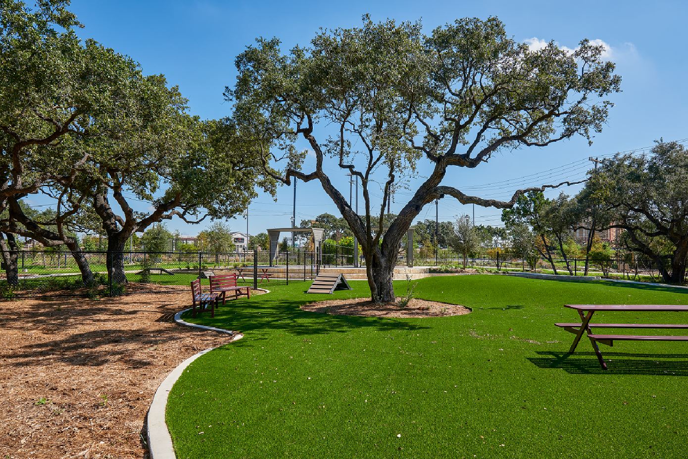 La Cantera Dog Park with grass, picnic tables, benches and shade trees
