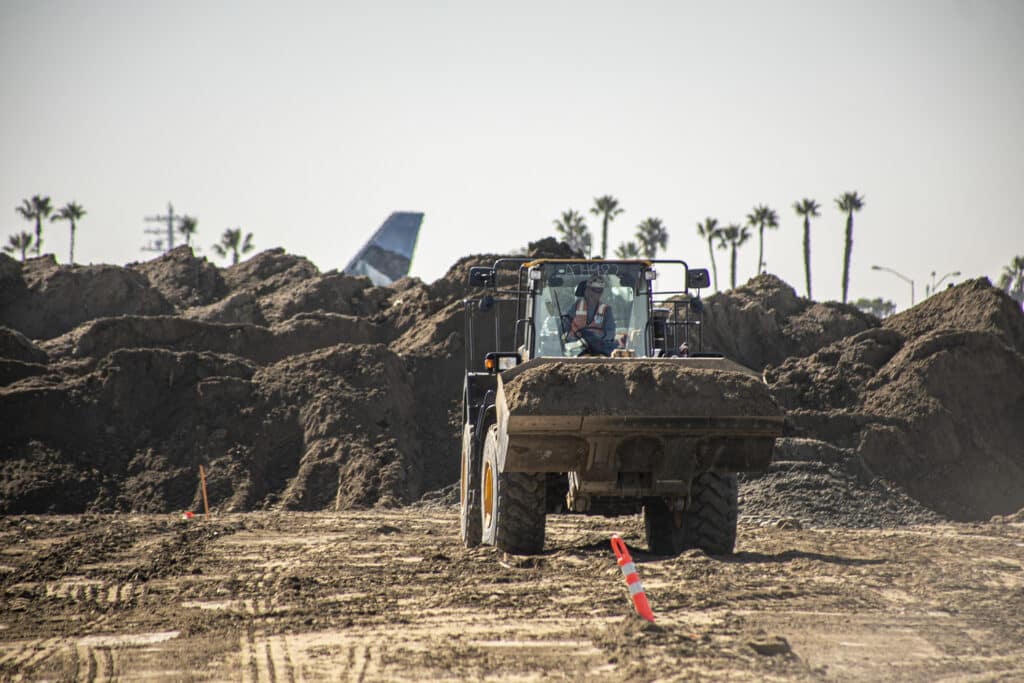 avión despega detrás del cargador haciendo movimiento de tierras en el Aeropuerto Internacional de San Diego