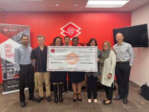 eight people holding a big check while posing for a picture