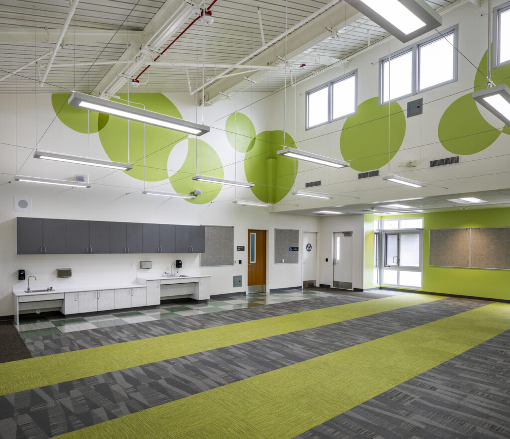vista del interior de un salón de clases de primaria renovado con techos abovedados y claraboyas