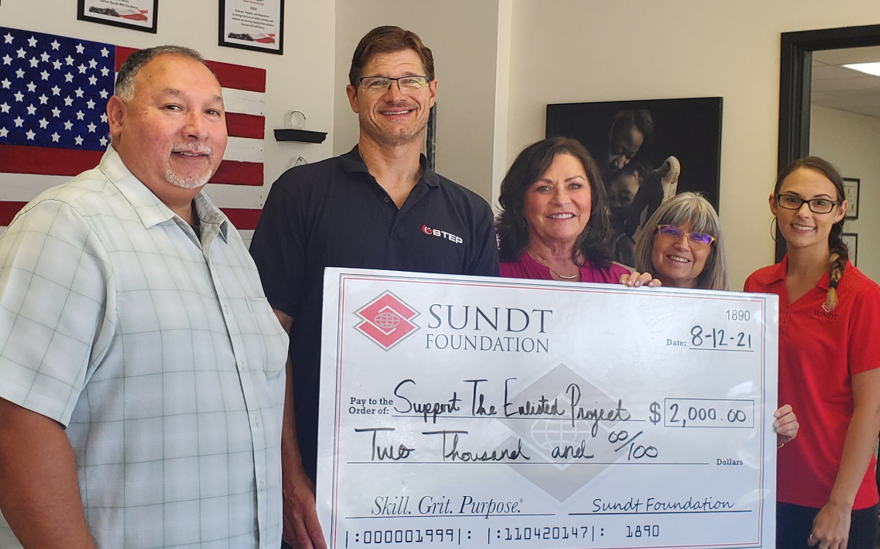 los miembros de la fundación sundt entregan un cheque a una organización sin fines de lucro enfocada en veteranos