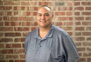 Man standing in front of a brick wall smiling for the photo