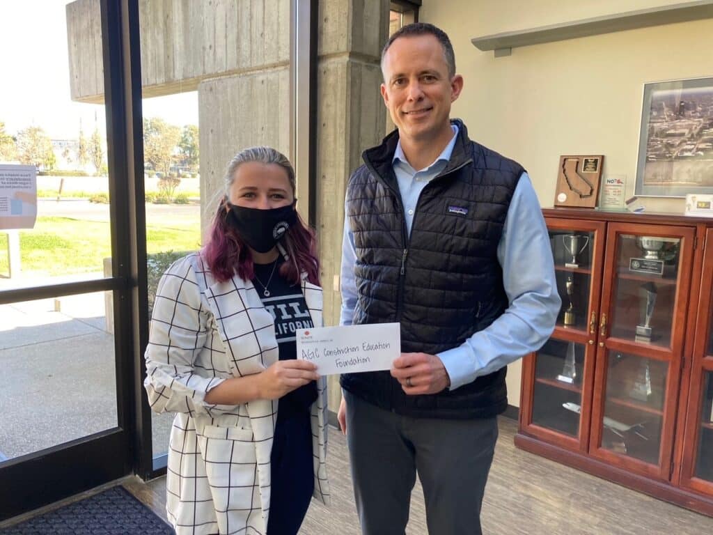 Two people holding a check in an office.