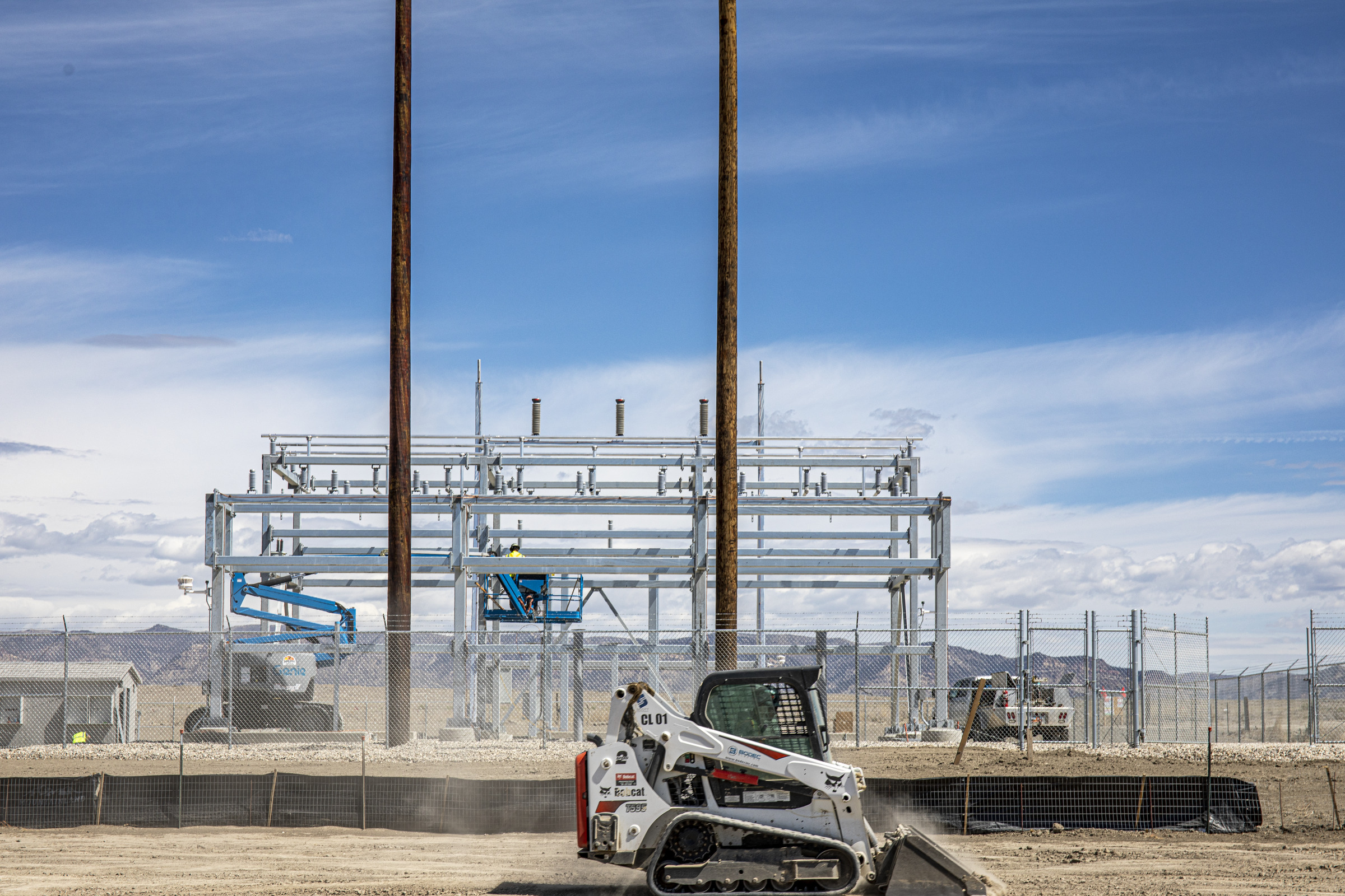 Excavator driving in front of an industrial construction project in the desert