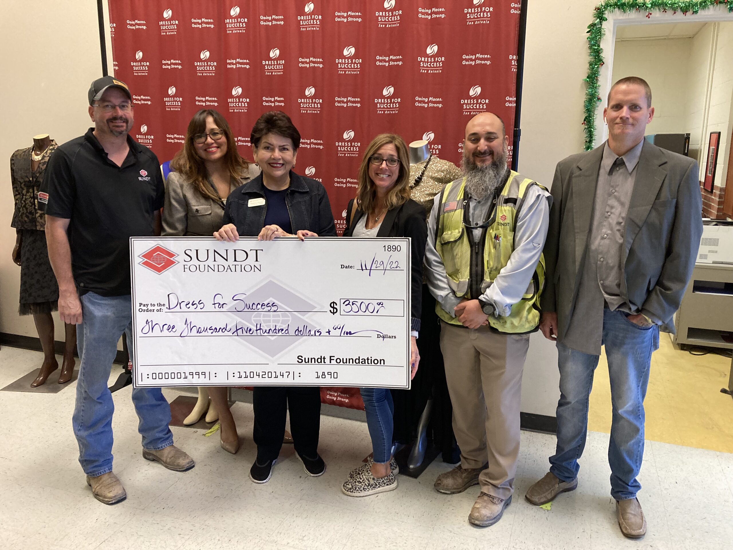 Professionally dressed individuals holding a large check